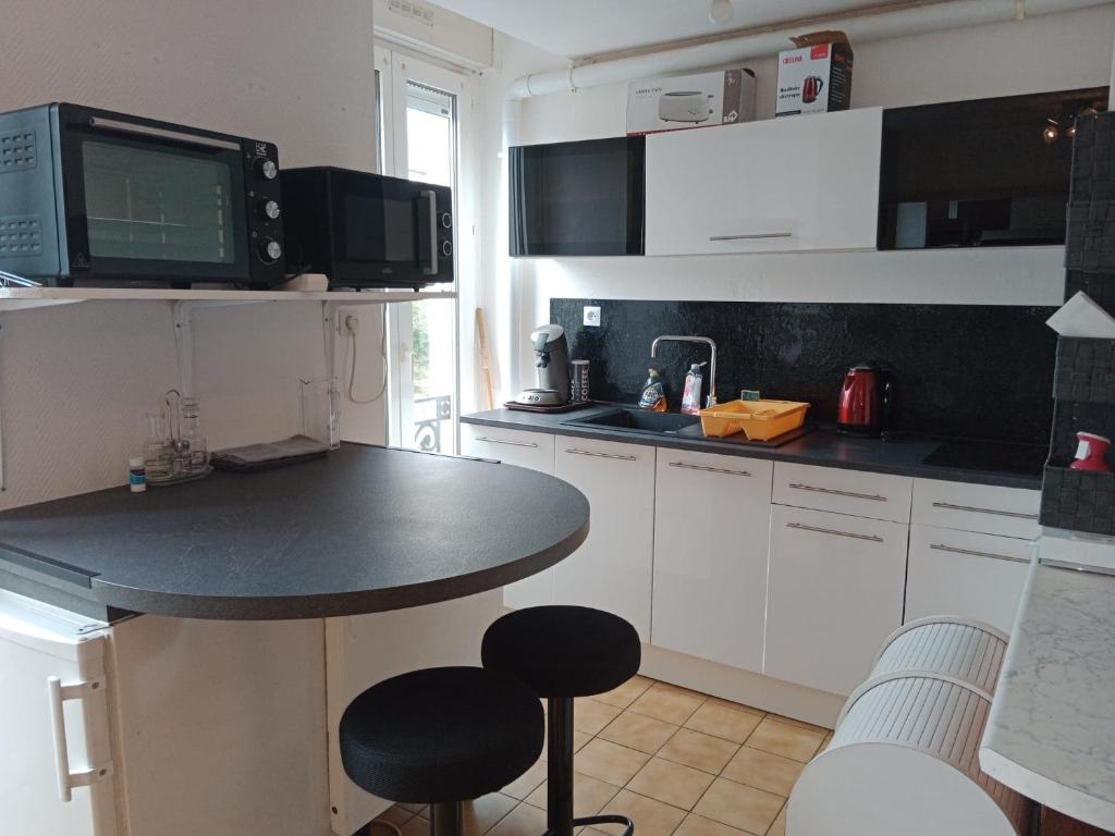 a kitchen with white cabinets and a black counter top at Vitré centre Ville bel appartement a découvrir in Vitré