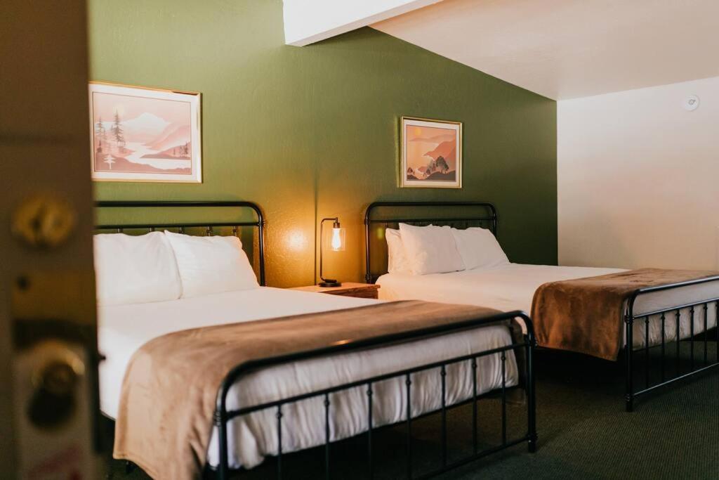 two beds in a room with green walls at The Long Barn Lodge in Long Barn