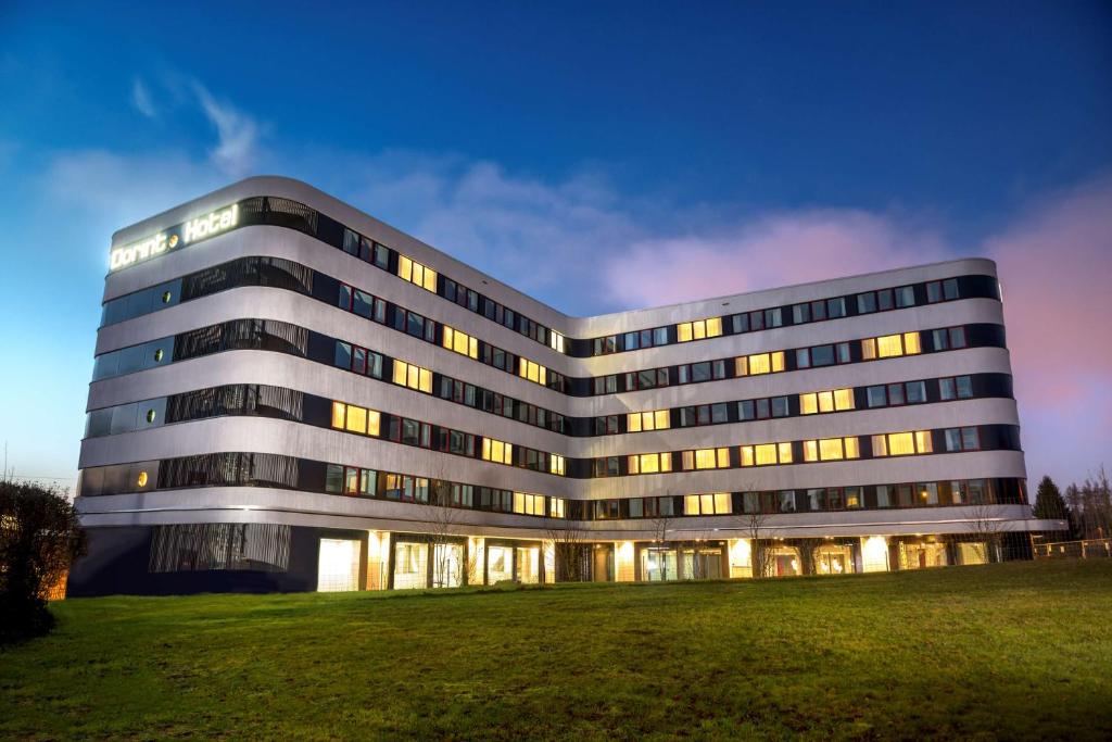 un gran edificio de oficinas con un campo de césped delante en Dorint Airport-Hotel Zürich, en Glattbrugg