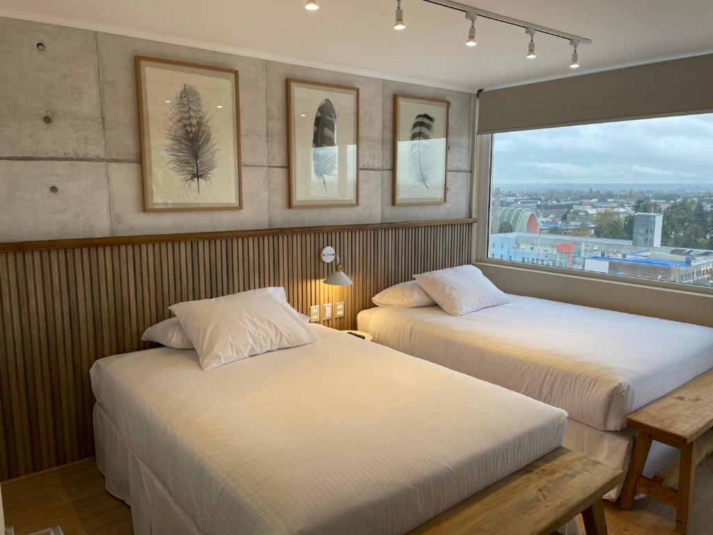 two beds in a hotel room with a window at Apart Hotel Las Terrazas Suite in Chillán