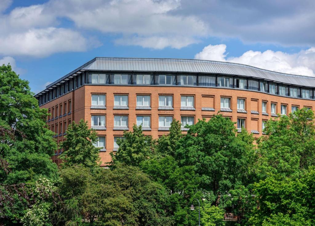 un bâtiment en briques avec des arbres devant lui dans l'établissement Dorint City-Hotel Bremen, à Brême