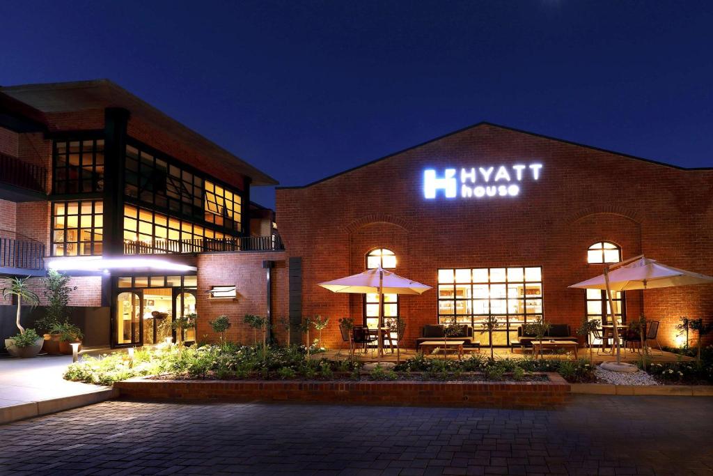 un gran edificio de ladrillo con un cartel iluminado en Hyatt House Johannesburg, Sandton en Johannesburgo