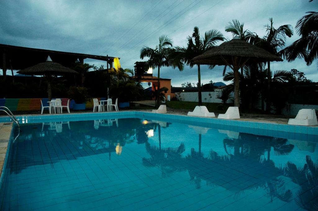 uma grande piscina com cadeiras e guarda-sóis em Hotel Marina Clube de Pesca em Cananeia