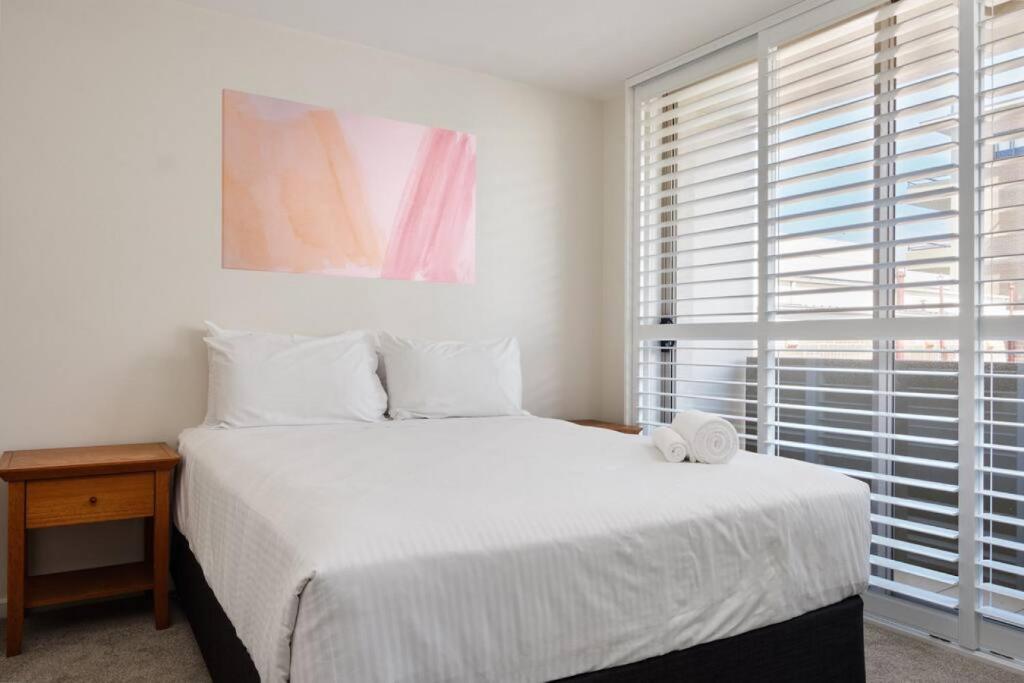 a bedroom with a large white bed and a window at Heart Of Manly and Close to Everything in Sydney