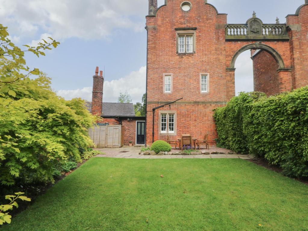 an old brick building with a lawn in front of it at South Tower Cottage in Macclesfield