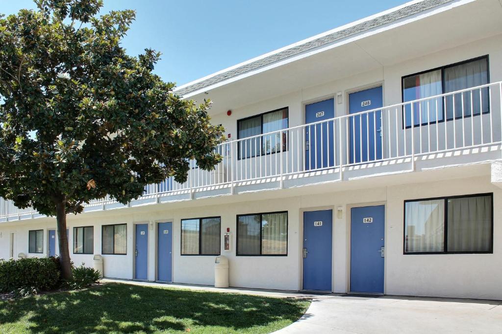 a building with blue doors and a tree at Motel 6-Atascadero, CA in Atascadero