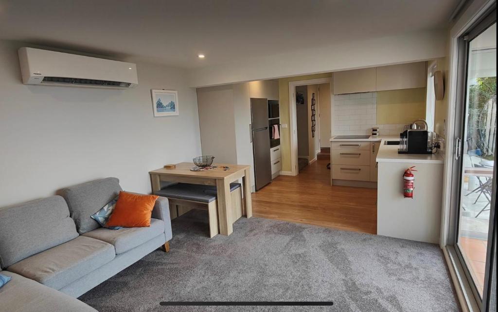 a living room with a couch and a kitchen at Fully Renovated Hillside Apartment Close To City in Christchurch