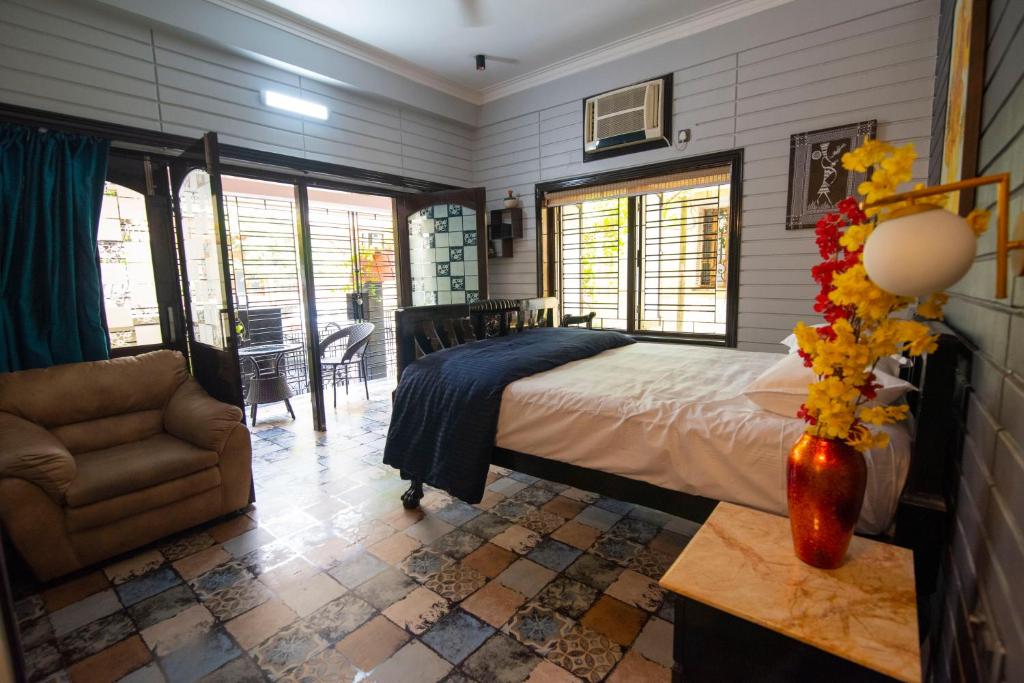 ein Schlafzimmer mit einem Bett, einem Stuhl und einem Tisch in der Unterkunft J's Nest in Kalkutta