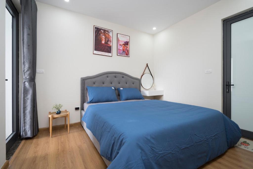 a bedroom with a blue bed in a white room at Mon Homestay Hạ Long in Ha Long