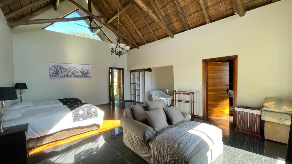 a bedroom with a bed and a couch in it at The Vaal Guesthouse in Oranjeville