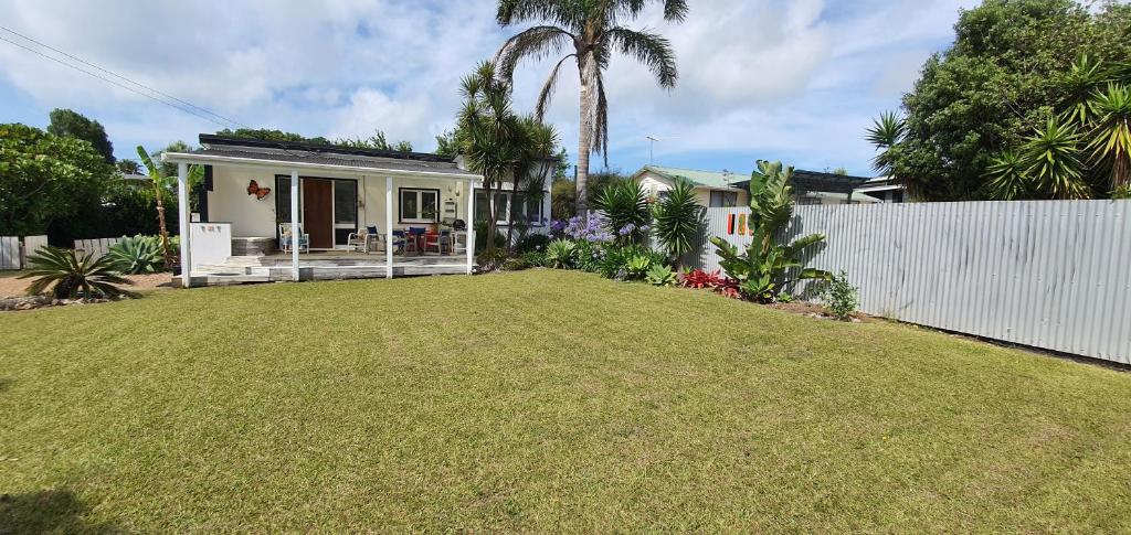 a backyard of a house with a white fence at Quintessential kiwi bach in Oneroa