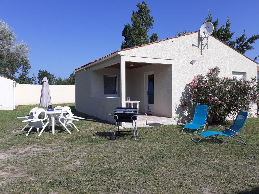 een achtertuin met stoelen en een grill en een huis bij Maison vacances d'Oléron in La Brée-les-Bains
