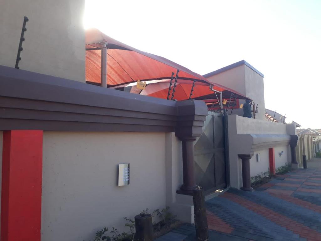 a building with a red roof and a red and white at Sunset View Palace Guest House in Soshanguve