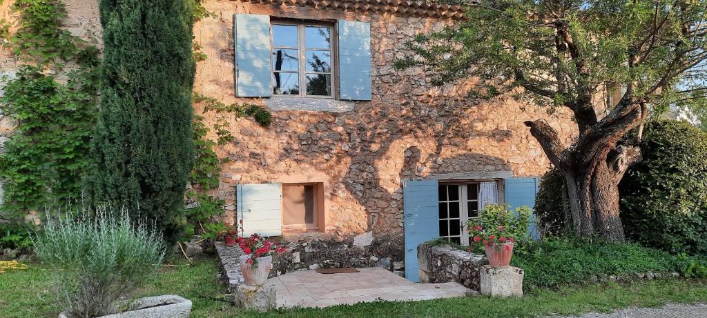 a stone house with a window and a tree at Gîte Les Fourches in Baudinard