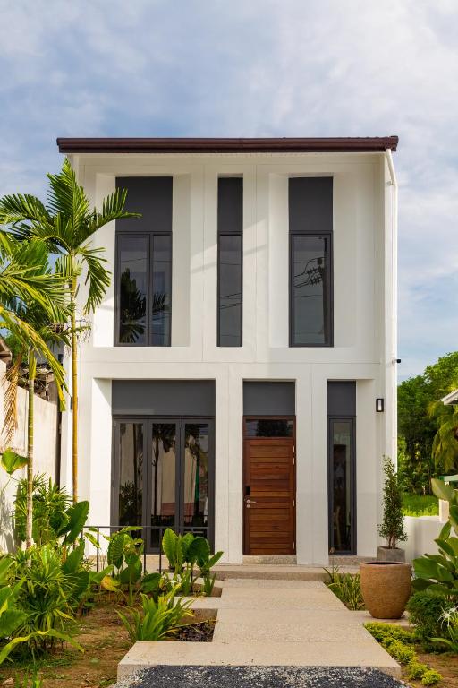 a white house with black windows and a wooden door at Baan Kamana Guest House in Phangnga