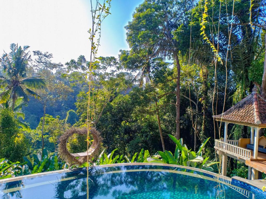 a resort swimming pool with a gazebo and trees at Made Punia's Jungle in Ubud