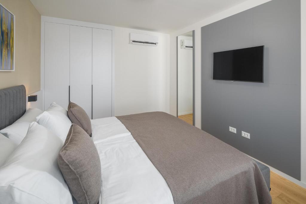 a bedroom with a bed with a television on the wall at Maj Luxury Residence in Poreč