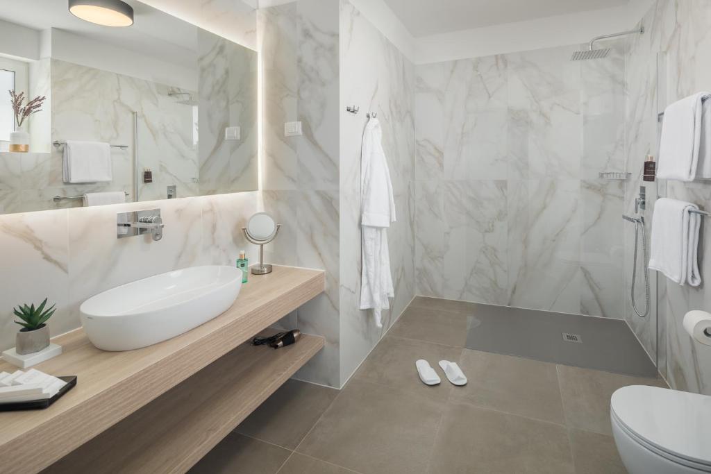 a white bathroom with a sink and a toilet at Maj Luxury Residence in Poreč