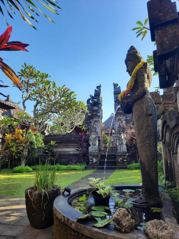 Una statua di una donna che annaffia un laghetto in un giardino di Sahadewa House ad Ubud