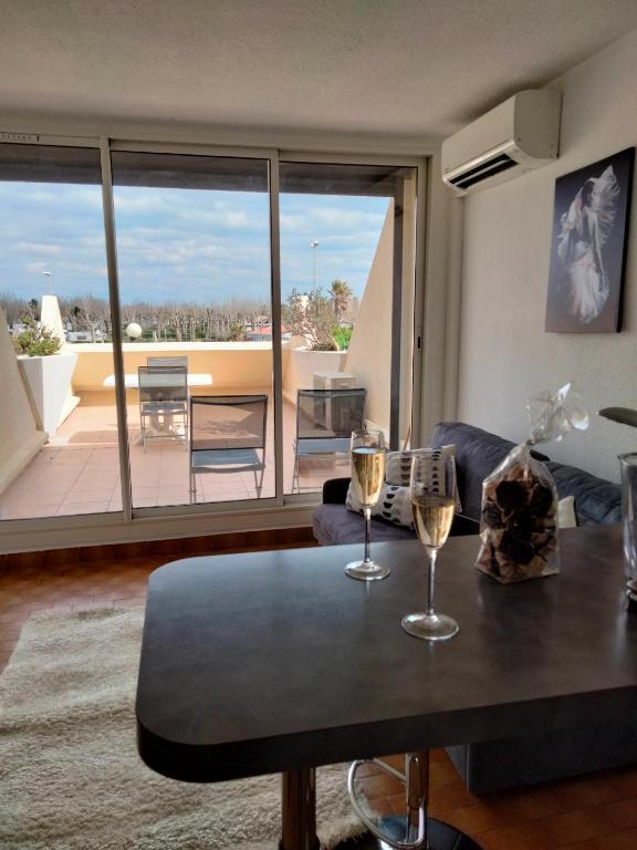 - un salon avec une table et deux verres de vin dans l'établissement Naturisme appartement heliopolis face à la plage avec vue mer, au Cap d'Agde