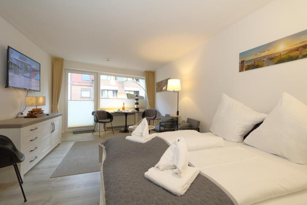 una camera da letto con un grande letto bianco e una scrivania di Kompass Sylt a Westerland