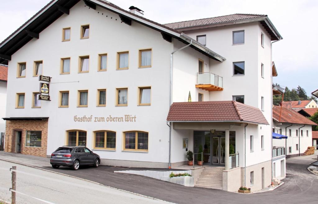 Biały budynek z samochodem zaparkowanym przed nim w obiekcie Hotel-Gasthof Zum Oberen Wirt w mieście Regen