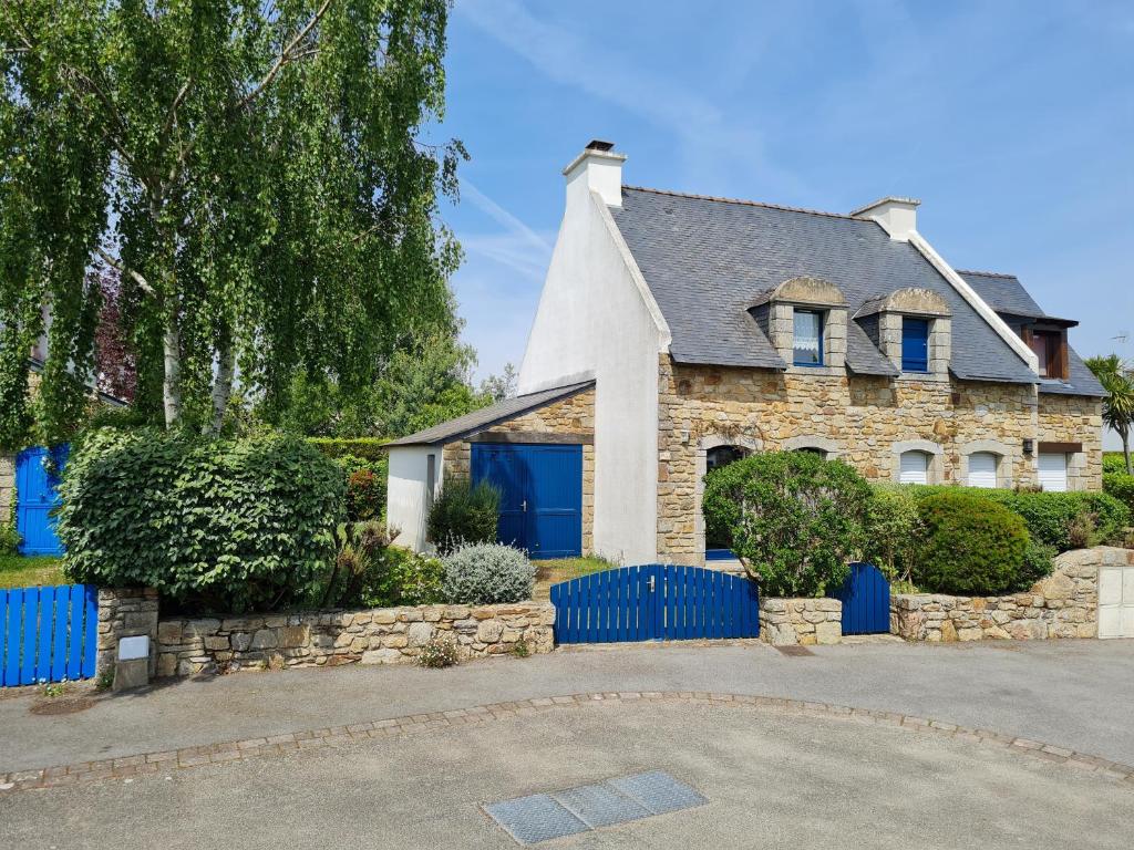 uma casa com uma cerca azul em frente em REF 035 - Belle maison en pierre pour quatre personnes proche Golfe du Morbihan ARZON em Arzon