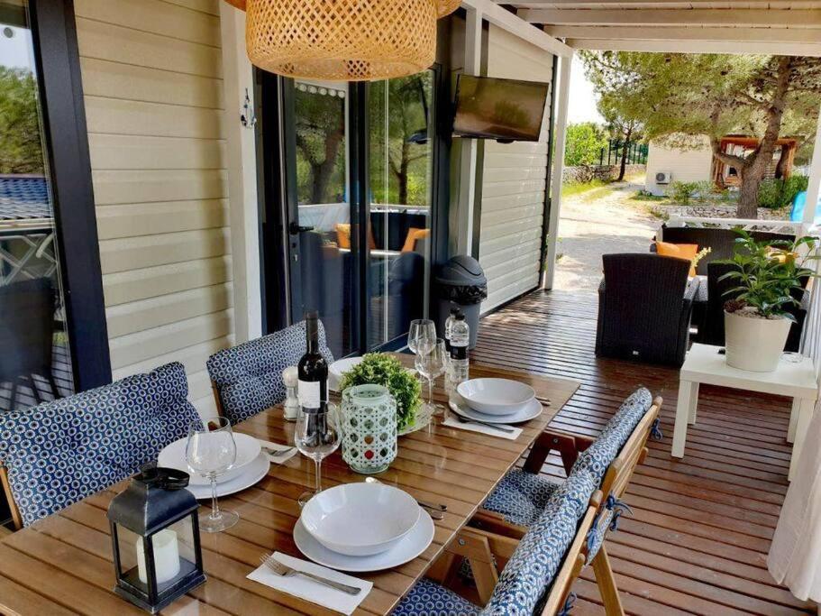 a table on a porch with chairs and a tableablish at Mobilheim ANDREA wunderschöne Ferienwohnung direkt am Meer in Jezera