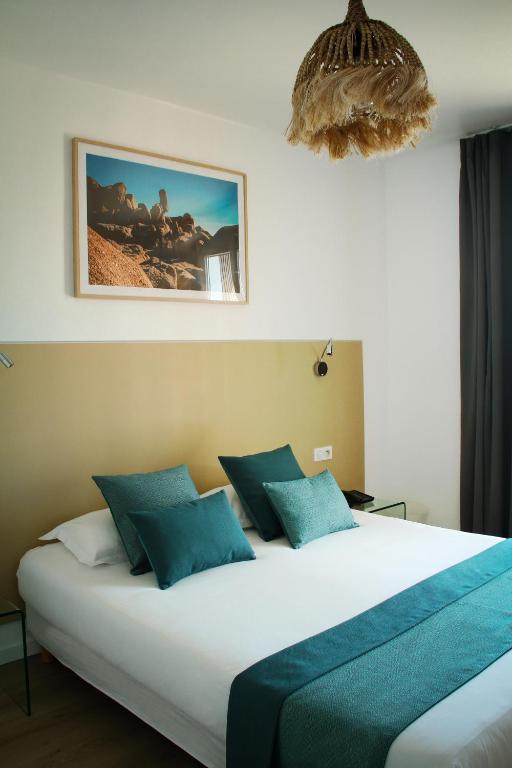 a bedroom with a large bed with blue pillows at Hotel l'Isolella in Porticcio