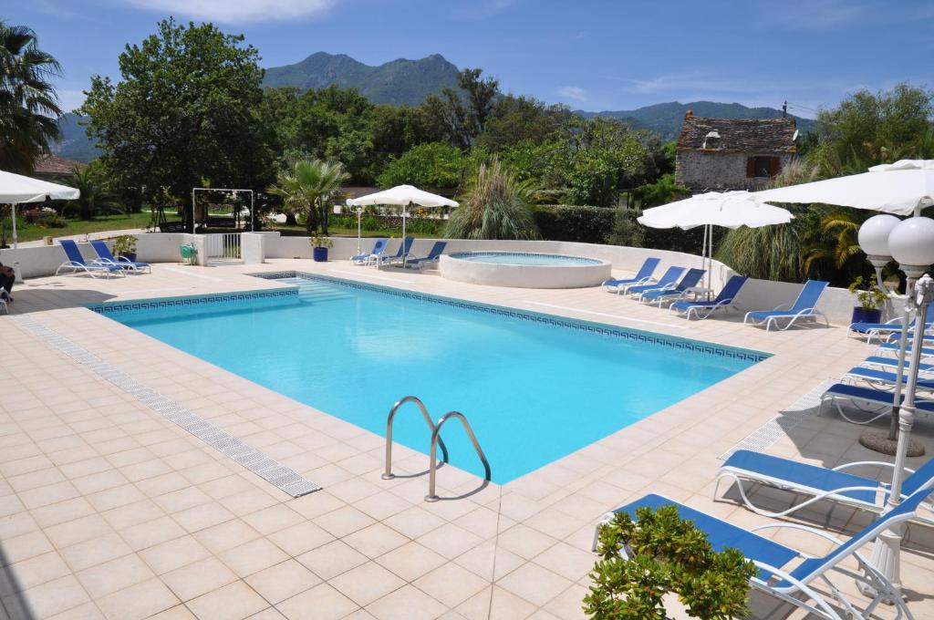 a large swimming pool with chairs and umbrellas at VILLA OCEANE in San-Nicolao