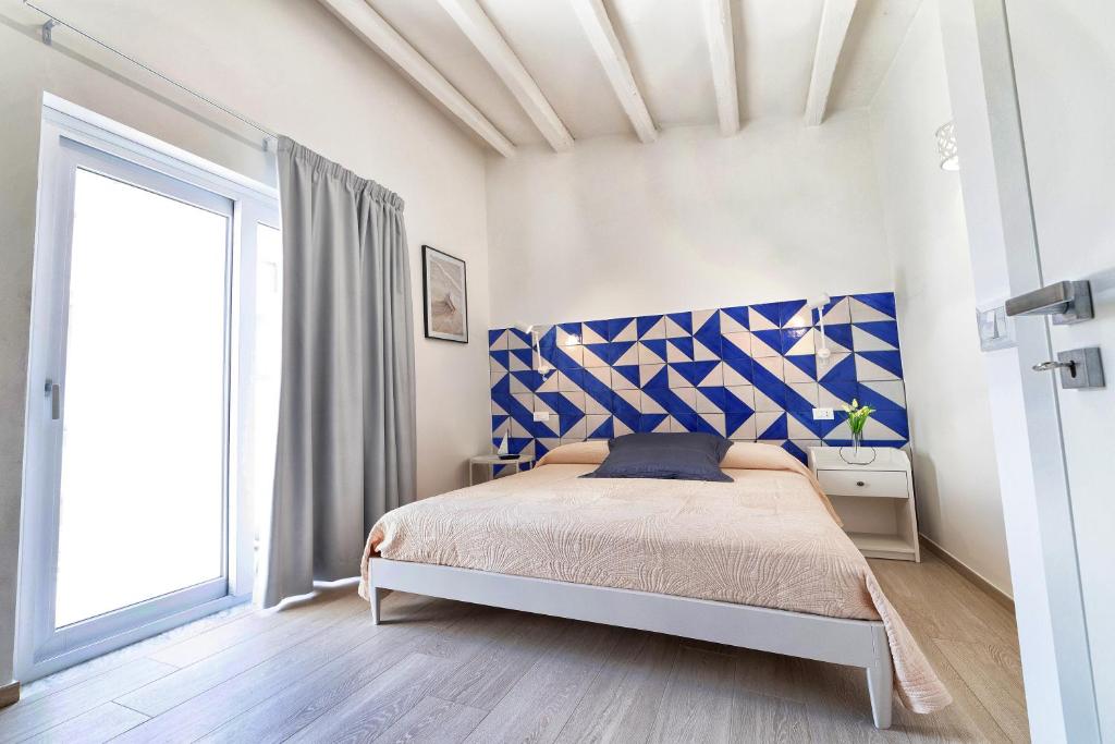 una camera con letto e testiera blu e bianca di Lo Scoglio della Formica B&B a Capo dʼOrlando