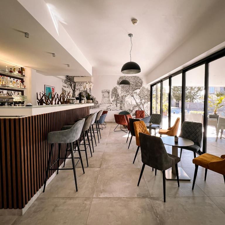a restaurant with a bar with chairs and tables at Hotel l'Isolella in Porticcio