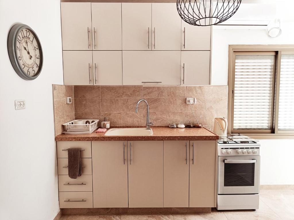 a kitchen with a sink and a clock on the wall at רקפת - יחידה במדבר in Arad