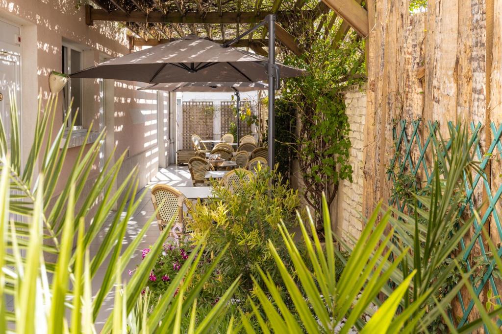 une terrasse avec une table, des chaises et un parasol dans l'établissement Logis Hôtel Rêve de Sable, à Royan