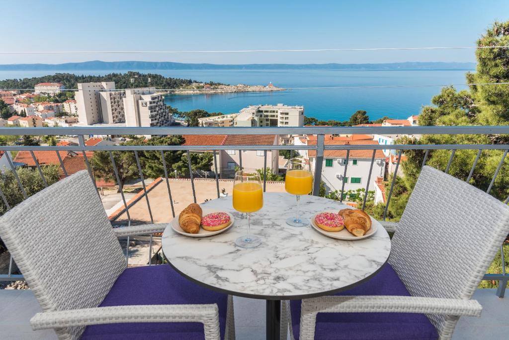 a table with food and drinks on a balcony at Milka Apartments in Makarska