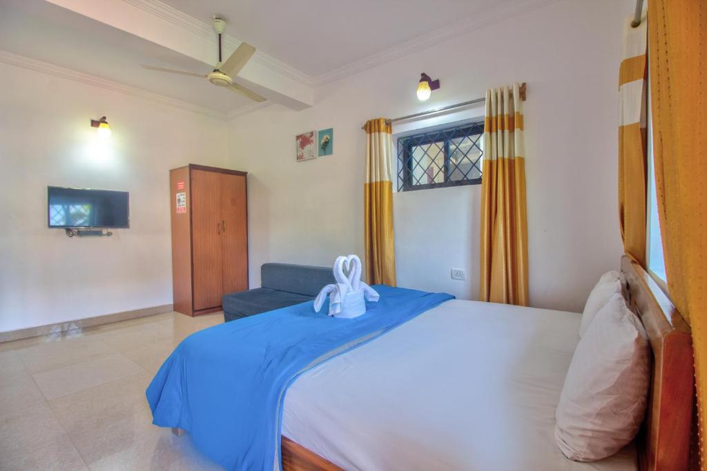 a bedroom with a large bed with a blue blanket at Hidden Caves Inn in Baga