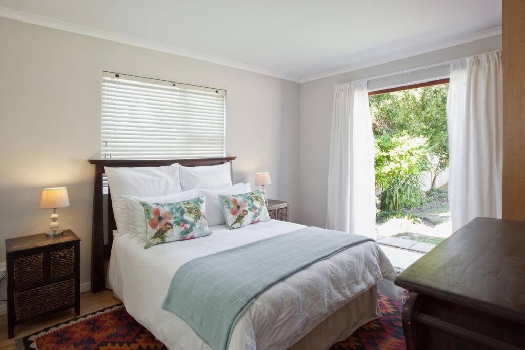 a bedroom with a bed and a large window at Sunbird Cottage in Somerset West