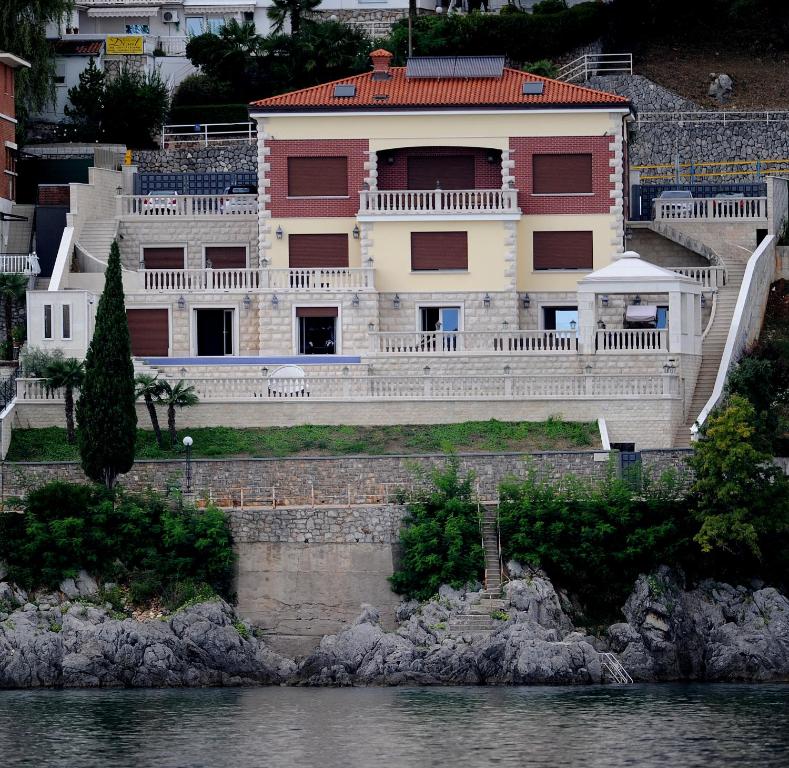 a large house next to a body of water at Apartments Villa Isabella in Opatija