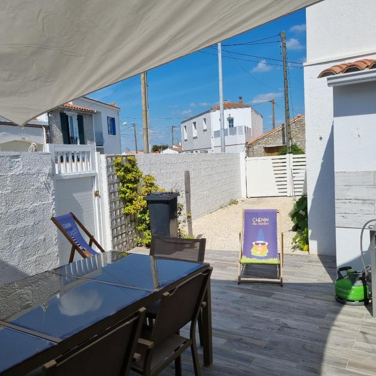 une terrasse avec une table, un panneau et une chaise dans l'établissement Maison typique vendéenne, à La Tranche-sur-Mer