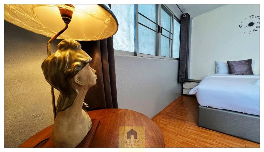 a statue of a woman sitting on a table with a lamp at Hooman Hostel in Chiang Mai