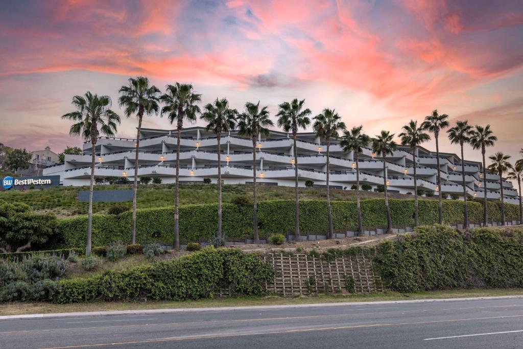 恩西尼塔斯的住宿－The Encinitan Hotel & Suites，一条街道前方有棕榈树的大型白色建筑