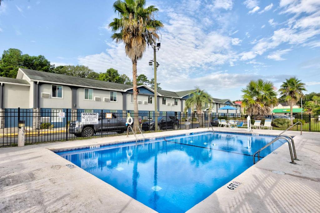 a swimming pool with a fence and palm trees at Days Inn by Wyndham Savannah Gateway I-95 in Savannah