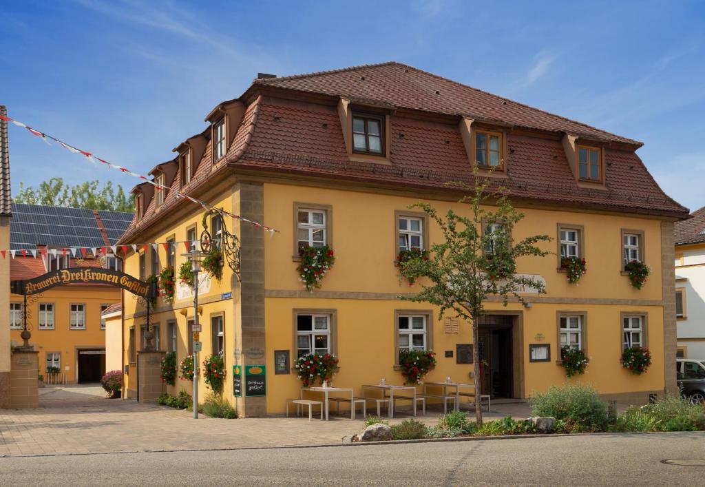 un bâtiment jaune avec des tables devant lui dans l'établissement Hotel & Brauereigasthof Drei Kronen, à Memmelsdorf