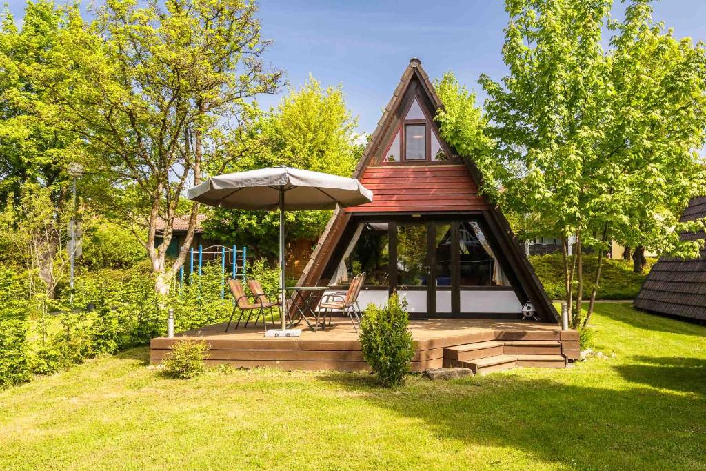 a small house with an umbrella and a chair at Ferienwohnpark Immenstaad am Bodensee Nurdachhaus Typ 7 ND 45 in Immenstaad am Bodensee