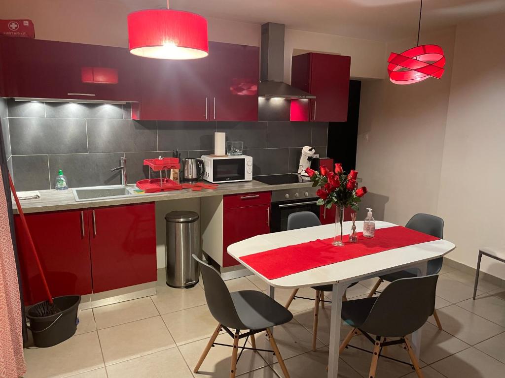 een keuken met rode kasten en een witte tafel met stoelen bij Red lights grand appartement in Saint-Étienne