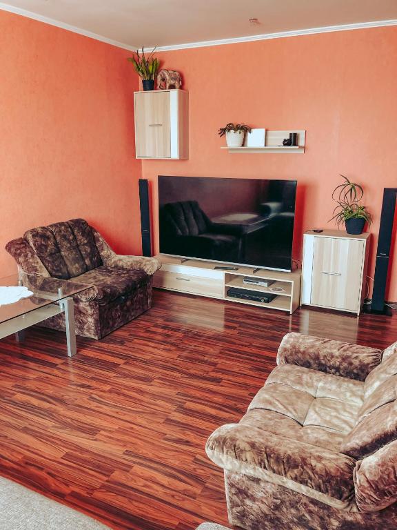 a living room with a television and a couch and chairs at Dzelmes in Kolka