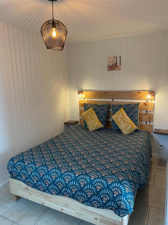 a bedroom with a bed with a blue comforter at Studio Terrasse Vue Lac Entrée indépendante in Font