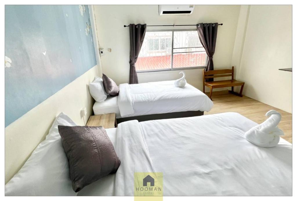 a hotel room with two beds and a window at Hooman Hostel in Chiang Mai
