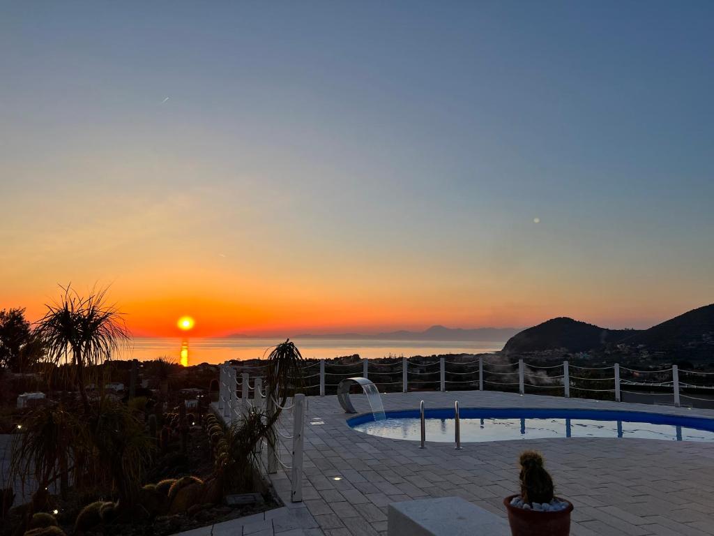 una persona sentada en un patio viendo la puesta de sol en infinity Castellabate b & b di Charme, en Santa Maria di Castellabate