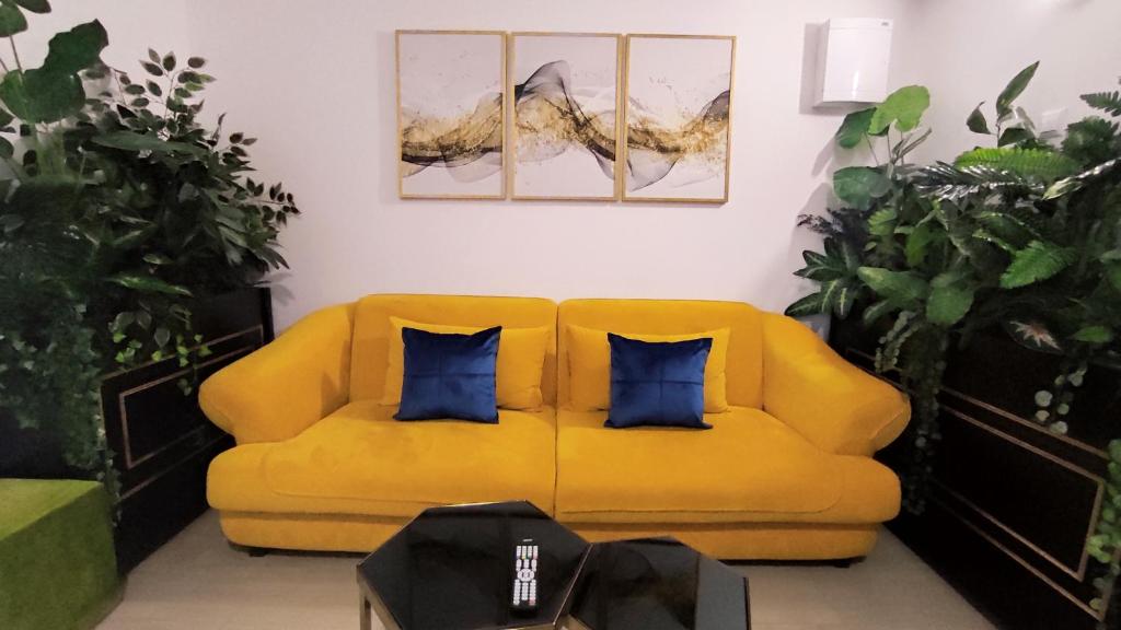 ein gelbes Sofa mit zwei blauen Kissen im Wohnzimmer in der Unterkunft Apartmani Abbazia in Banja Luka